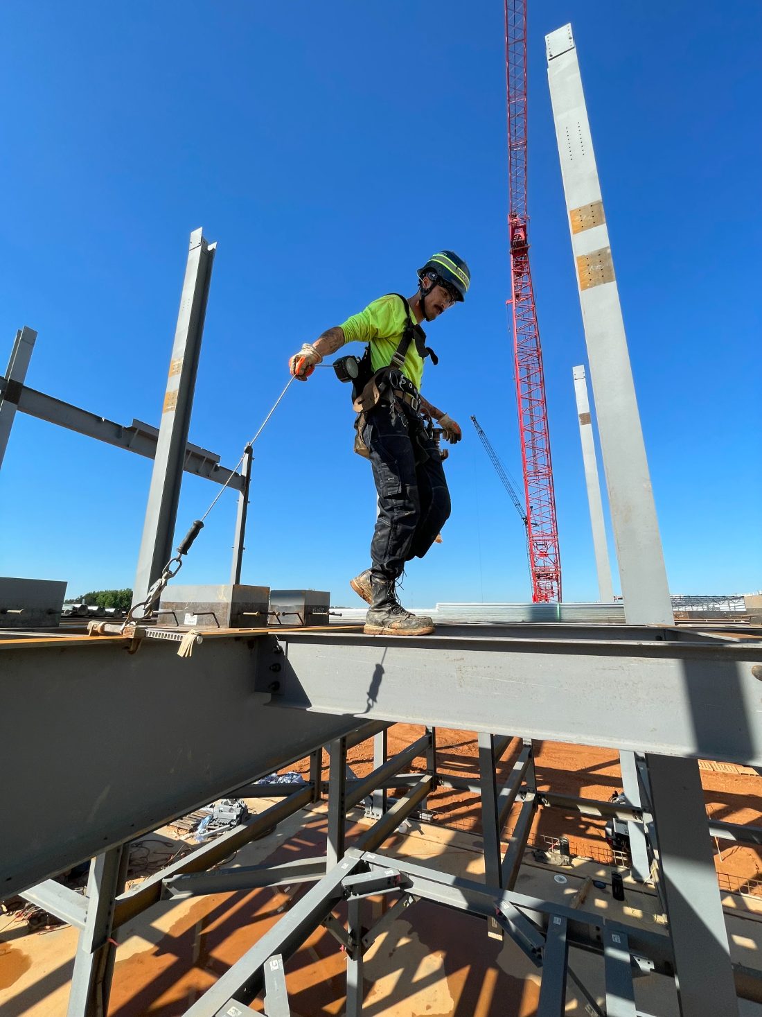 Diego Freitas-Bell, founder of billWright, walking structural steel on a job site at FeC Ironworks